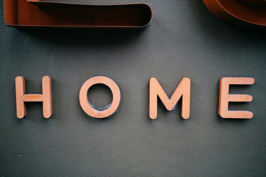 Artistic photo of 'HOME' letters on a textured gray wall. Ideal for interior design themes.