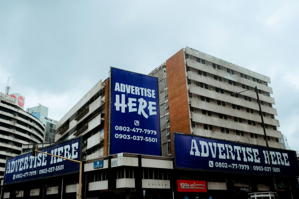 Large billboards on urban buildings displaying 'Advertise Here' in Lagos, Nigeria.