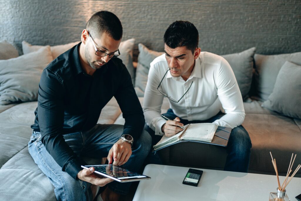 Two businessmen working together with a tablet and notebook in a contemporary home office space.
