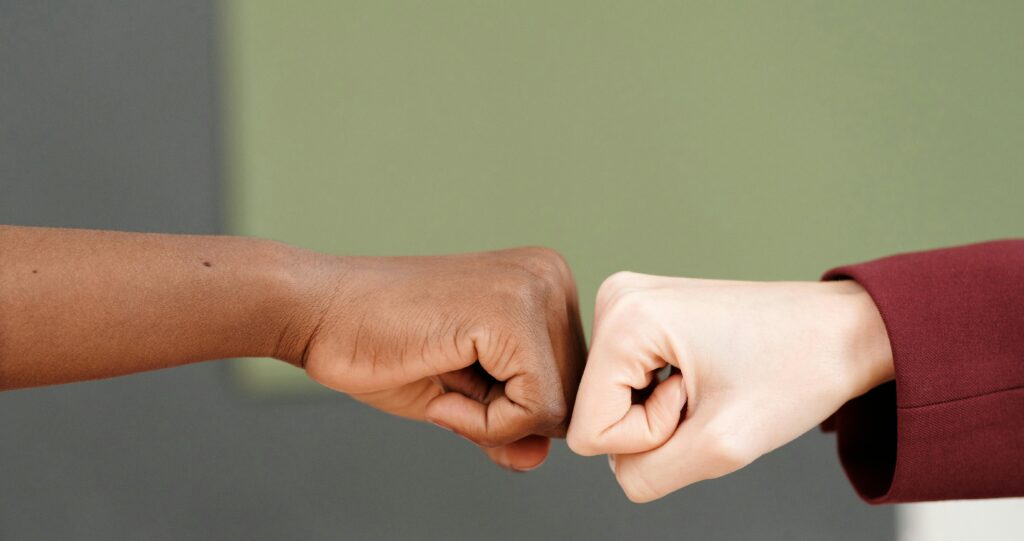 Close-up of two individuals exchanging a fist bump, symbolizing unity and teamwork.