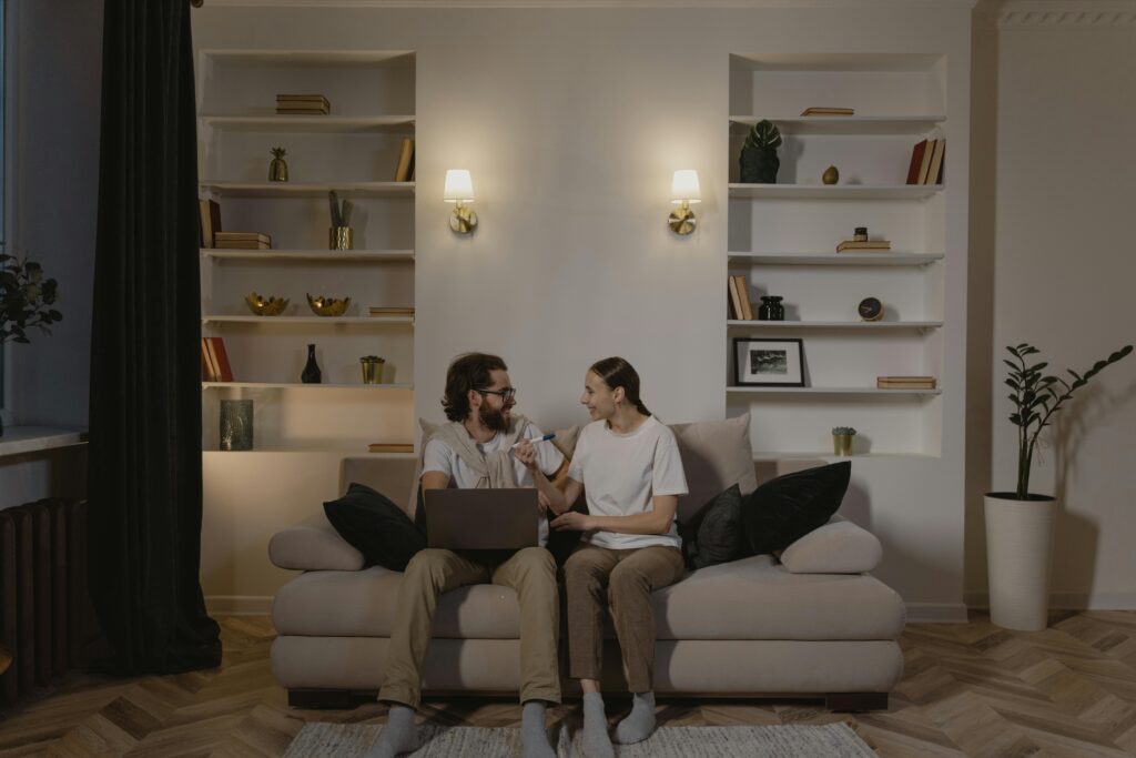 Smiling couple sitting on a couch at home, enjoying a relaxed and joyful moment.
